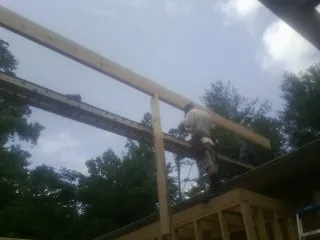 Carpenter setting a ridge beam over a new addition frame — Ice Dam Removal by Roofing Brothers in Granite Falls