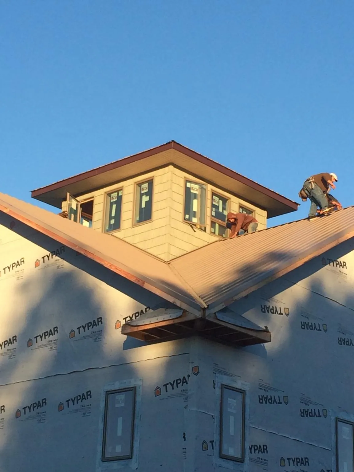 Roofers working around a rooftop cupola on a new metal roof at sunset — Roof Waterproofing in Granite Falls by Roofing Brothers